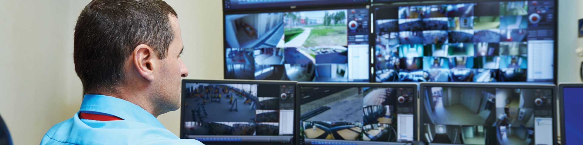 Security guard monitoring multiple surveillance screens
