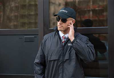 Security guard with earpiece and sunglasses outside building